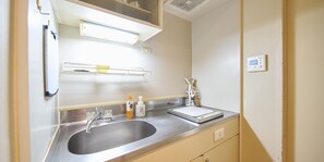 A modern bathroom with a stainless steel sink, a mirror, a towel rack, and a soap dispenser.