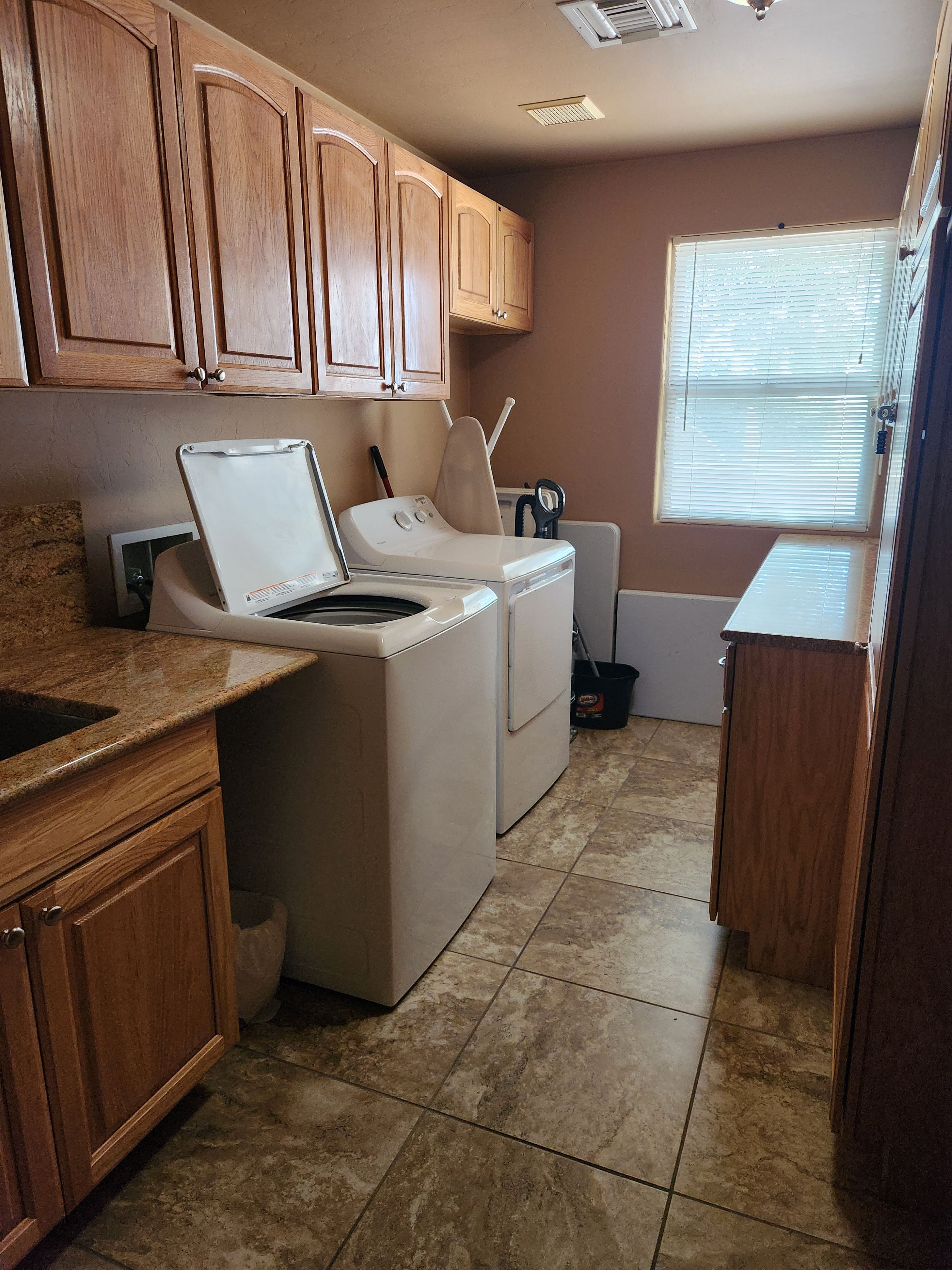 A laundry area with a washing machine, dryer, and ironing board.