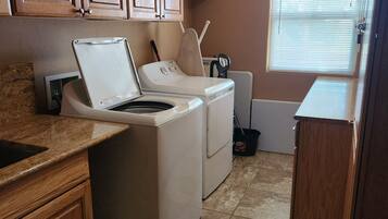 A laundry area with a washing machine, dryer, and ironing board.