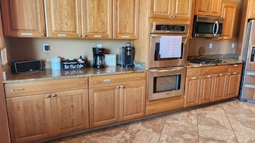 Una cocina con armarios de madera, electrodomésticos de acero inoxidable y encimera de granito.
