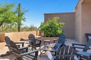 An outdoor patio with Adirondack chairs, a fire pit, and a potted plant. - Luxury Desert Retreat w/ Pool, Hot Tub & Stunning Views - private 5+ acres (Tucson)
