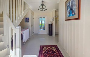 A hallway with a staircase, a door with a glass panel, a black cylindrical object, and a framed painting on the wall. - Nice home in Stabbestad (Stabbestad)