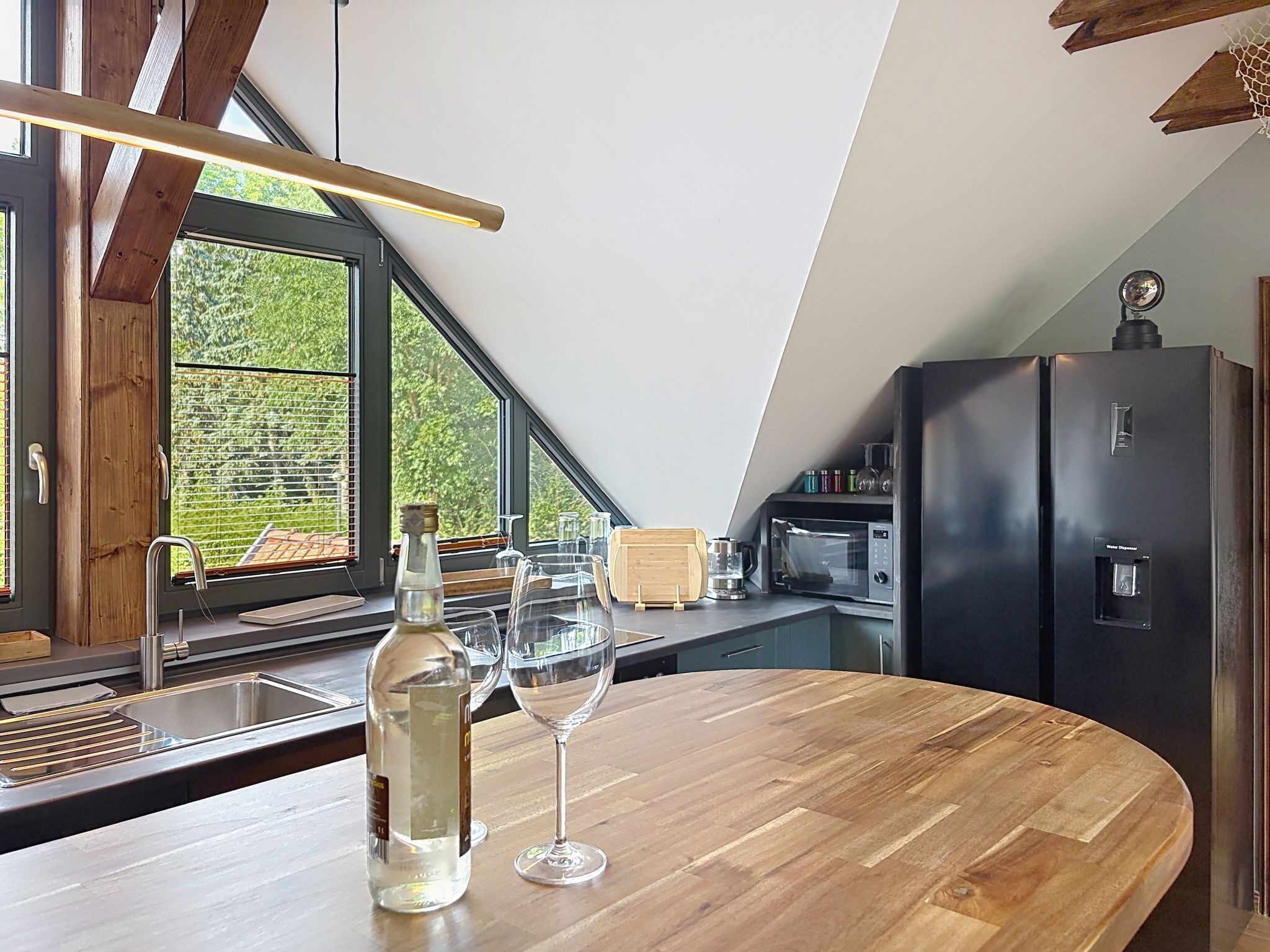 A modern kitchen with a wooden countertop, a wine bottle, and glasses.