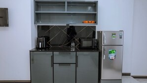 Una cocina compacta con microondas integrado, cafetera y refrigerador.