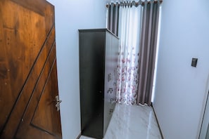 A hallway with a wooden door, a metal cabinet, and a window with curtains.