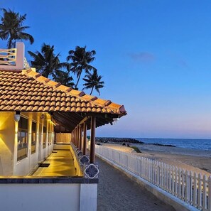 Hotel a primera línia de mar amb un passadís cobert, palmeres i vistes a l'oceà.