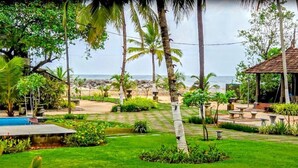 Un giardino rigoglioso con una piscina, palme e vista sull'oceano.