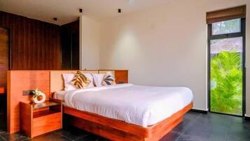 A modern bedroom with a wooden bed frame, a nightstand, and a window with a view of greenery.