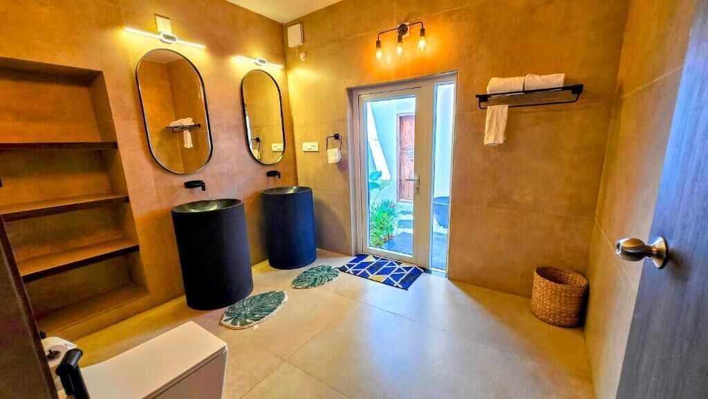 Un baño moderno con un espejo grande, dos lavamanos y una zona de ducha.