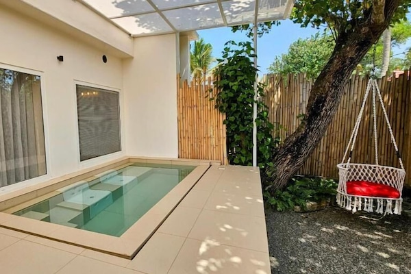 Una piscina al aire libre, sombrillas, sillones reclinables de piscina