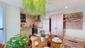 Eine moderne Küche mit Holzschränken, einer hängenden Pflanze und einem Esstisch, gedeckt mit Tellern und einer Vase.