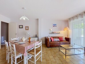 Un comedor con una mesa dispuesta para cuatro personas, un sofá de cuero marrón y una mesa de centro de vidrio.