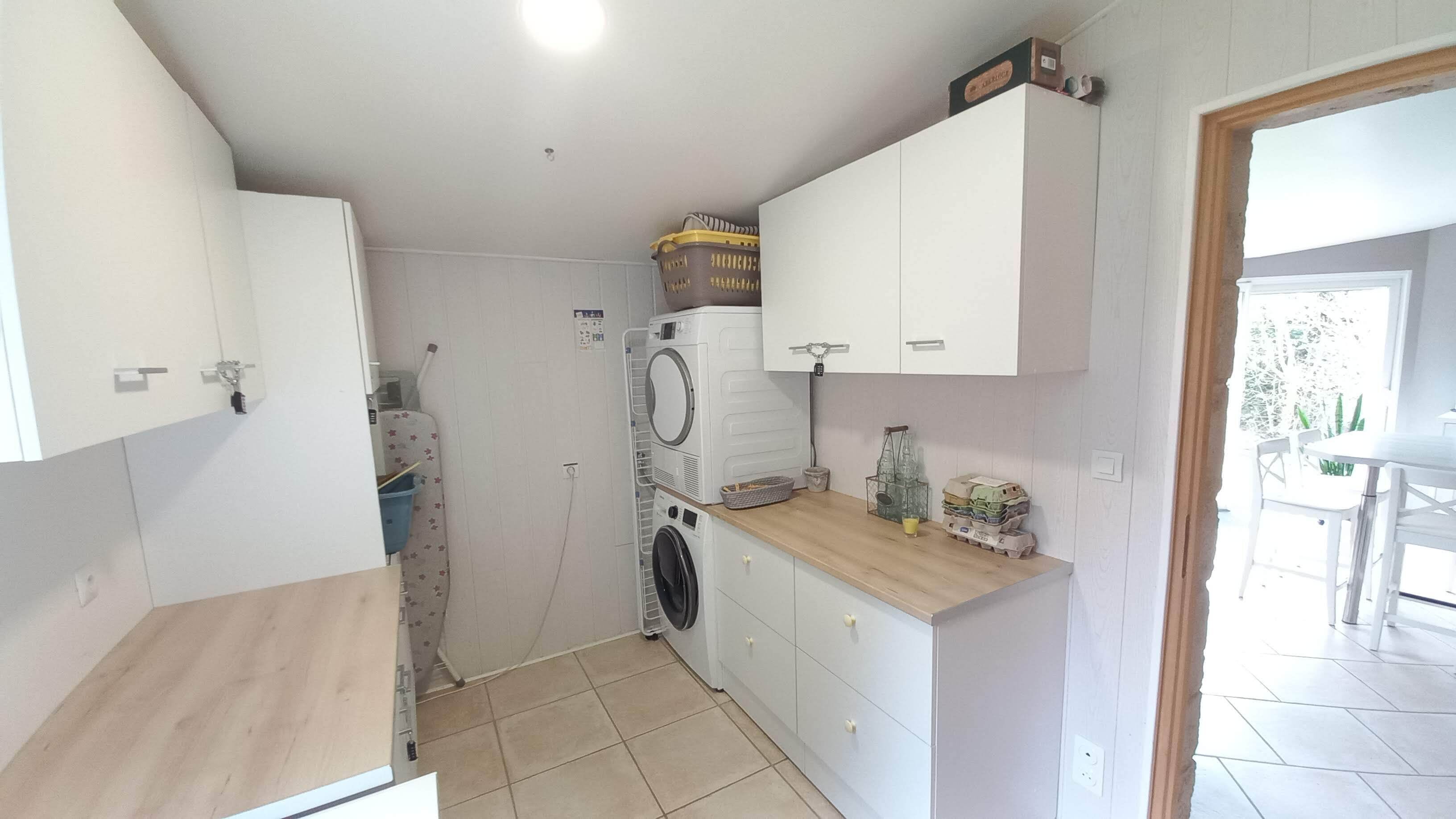 Uma cozinha compacta com máquina de lavar, varal e um pequeno balcão com recipientes de armazenamento.