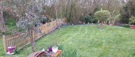 Un jardin bien entretenu, agrémenté d’une clôture en bois, de différentes plantes en pot et d’un petit étang.