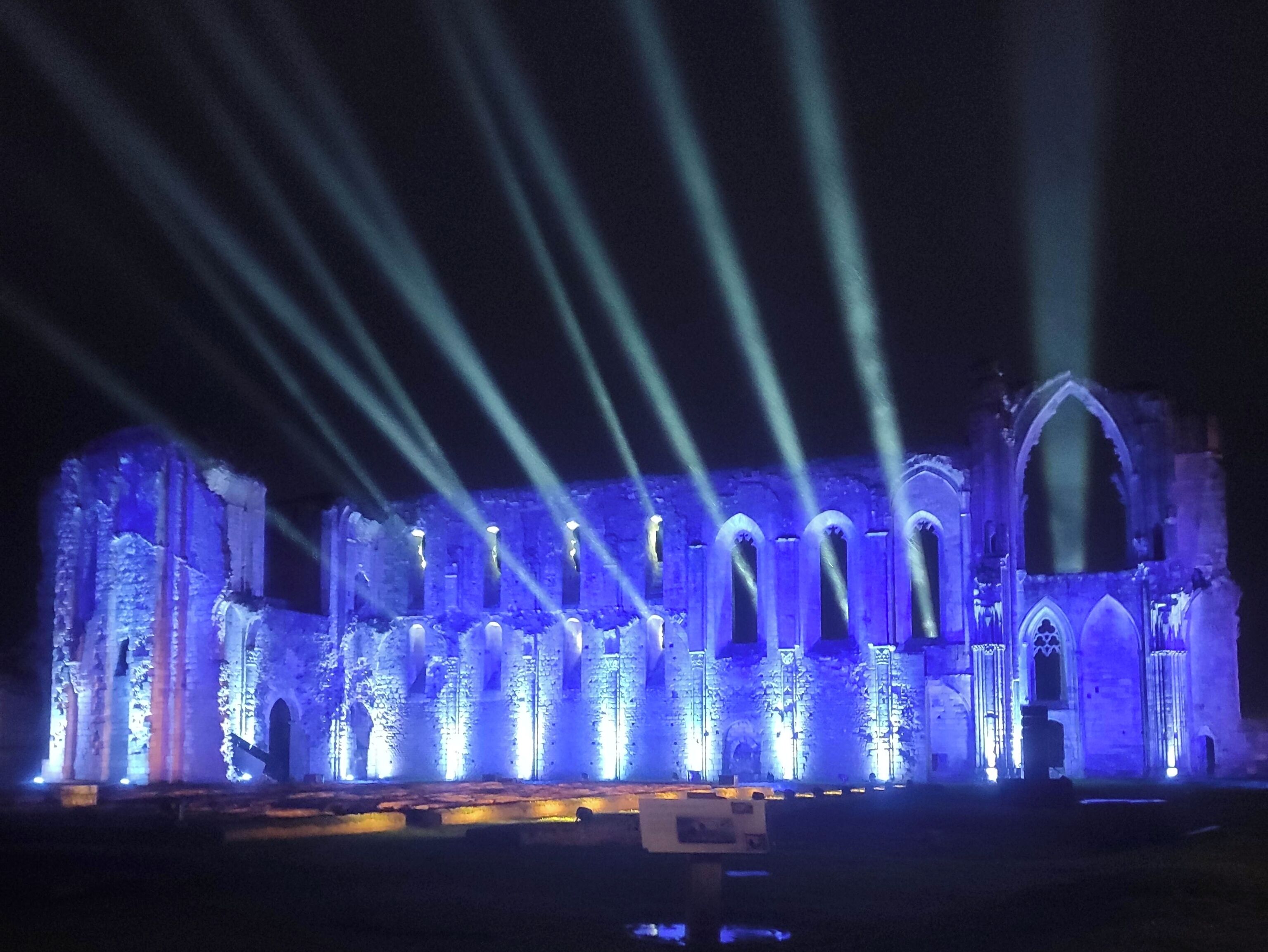 Ein historisches Gebäude, das blau beleuchtet und mit Lichtstrahlen erhellt ist.
