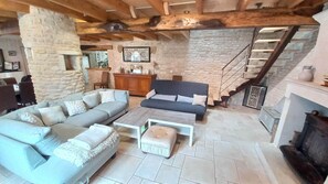 Ein geräumiger Wohnbereich mit Steinwand, Holztreppe und Kamin.