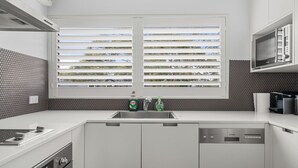 Una cocina moderna con un lavamanos doble, lavavajillas y una ventana con persianas.