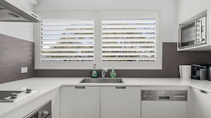 Eine moderne Küche mit einer Spüle, einem Geschirrspüler und einem Fenster mit Jalousien.