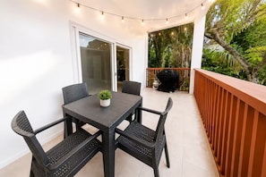 Eine Terrasse im Freien mit Tisch, Stühlen, einem Grill und Lichterketten.