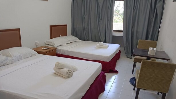 A hotel room with two beds, a small table, a chair, and a window with curtains. - VKB FERRINGHI STYLES PENANG GRAND STAR  (George Town)