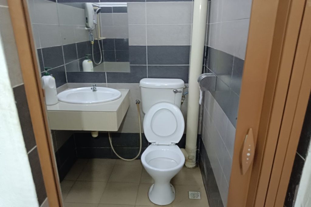 A small bathroom with a toilet, sink, and a mirror.