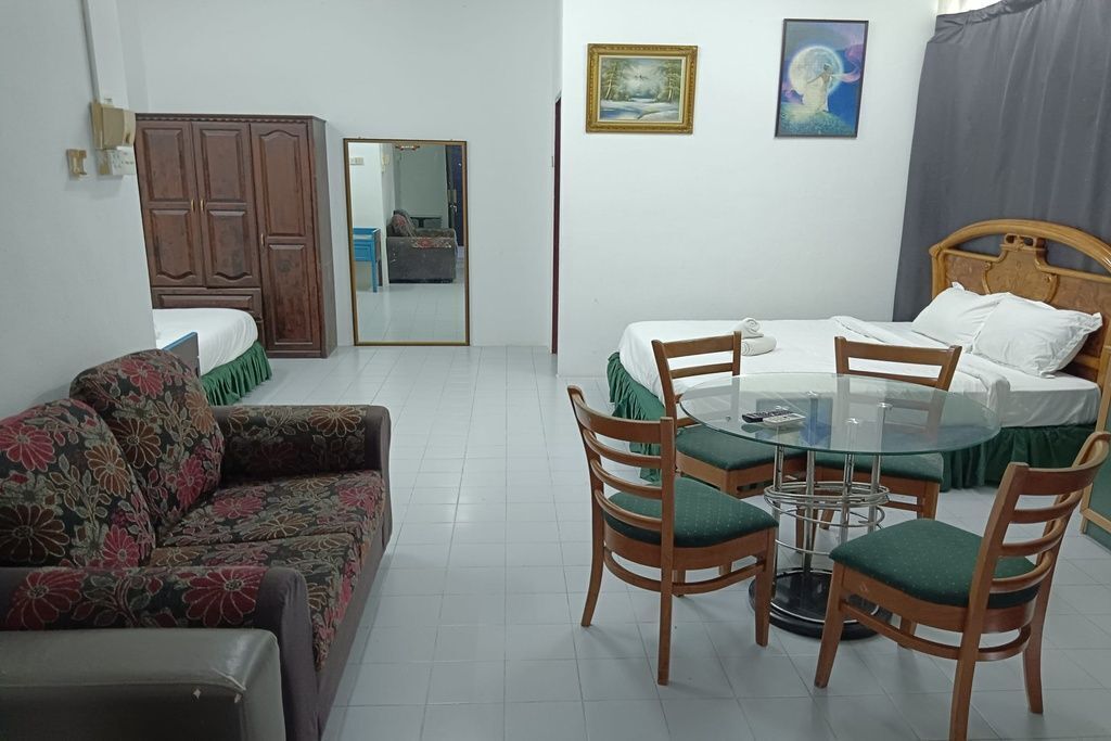 A room with a bed, a sofa, a dining table with chairs, a wardrobe, and two paintings on the wall.