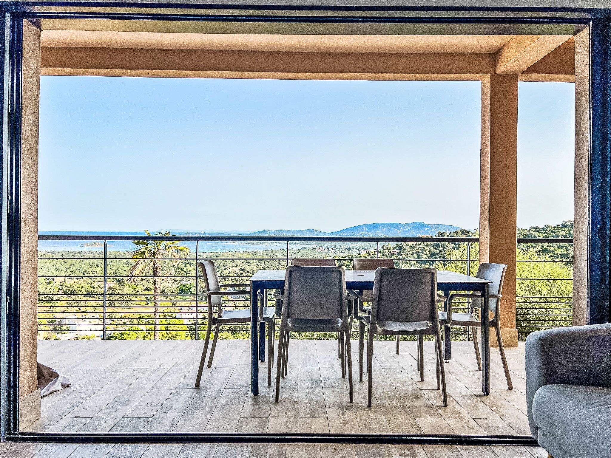 A balcony with a table and chairs, overlooking a scenic landscape with mountains and greenery.