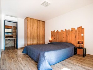 A bedroom with a large bed, wooden headboard, a nightstand with a lamp, and a wardrobe. - Dea Mare by Interhome (Sainte Lucie Porto Vecchio)