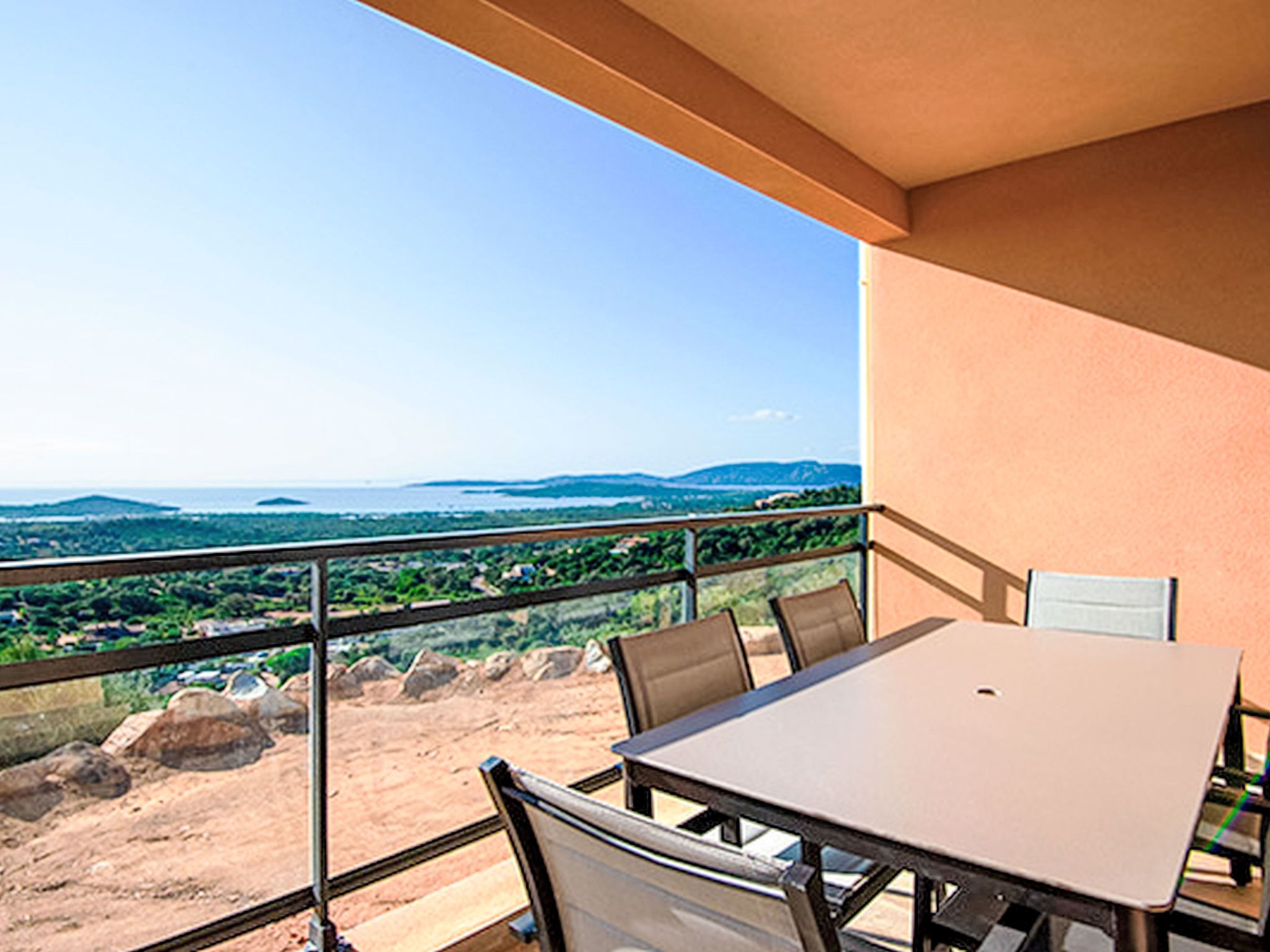 Ein Balkon mit Tisch und Stühlen, mit Blick auf eine Landschaft aus Hügeln und Bäumen.