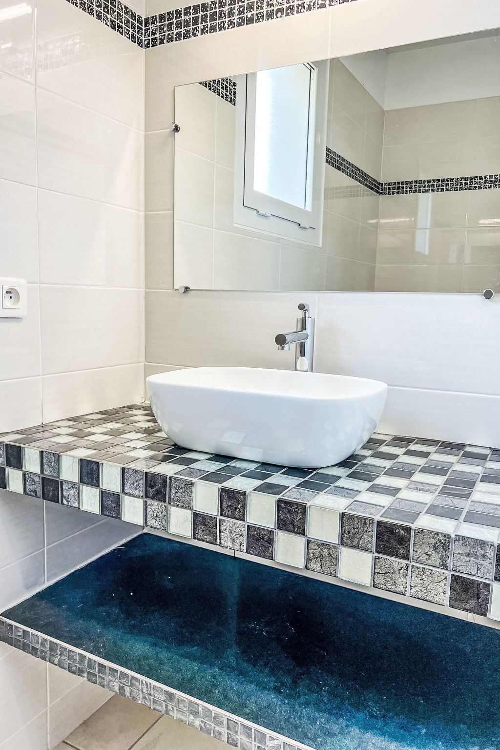 Un bany amb un lavabo blanc, un mirall i una petxina rebedor.