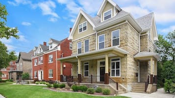 A two-story house with a front porch, a stone facade, and a well-maintained lawn.