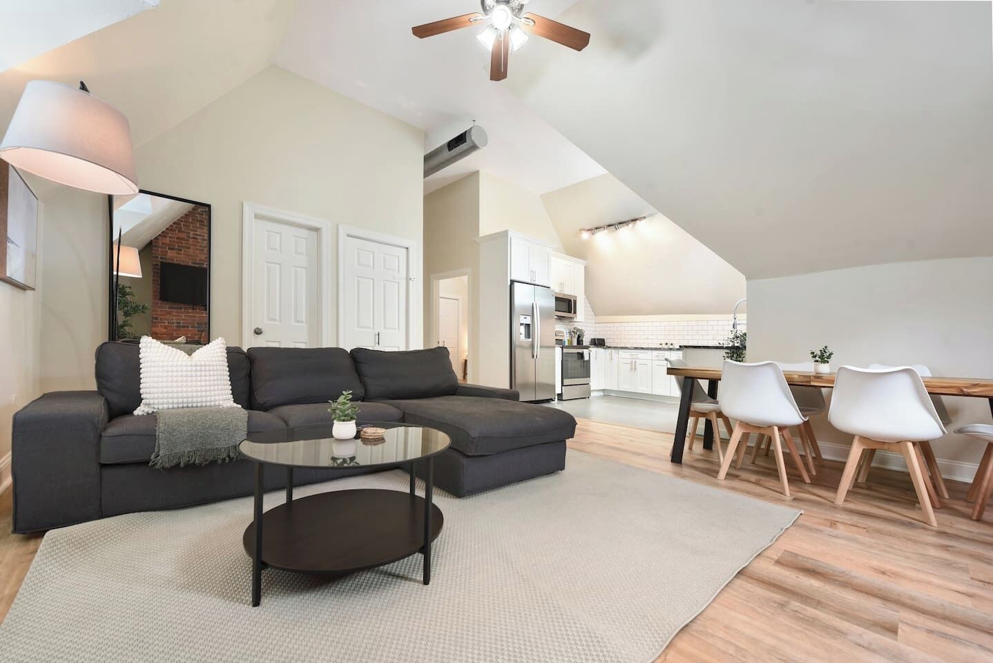 A modern living space with a sectional sofa, a coffee table, and a dining area with chairs.