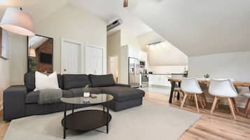 A modern living space with a sectional sofa, a coffee table, and a dining area with chairs.