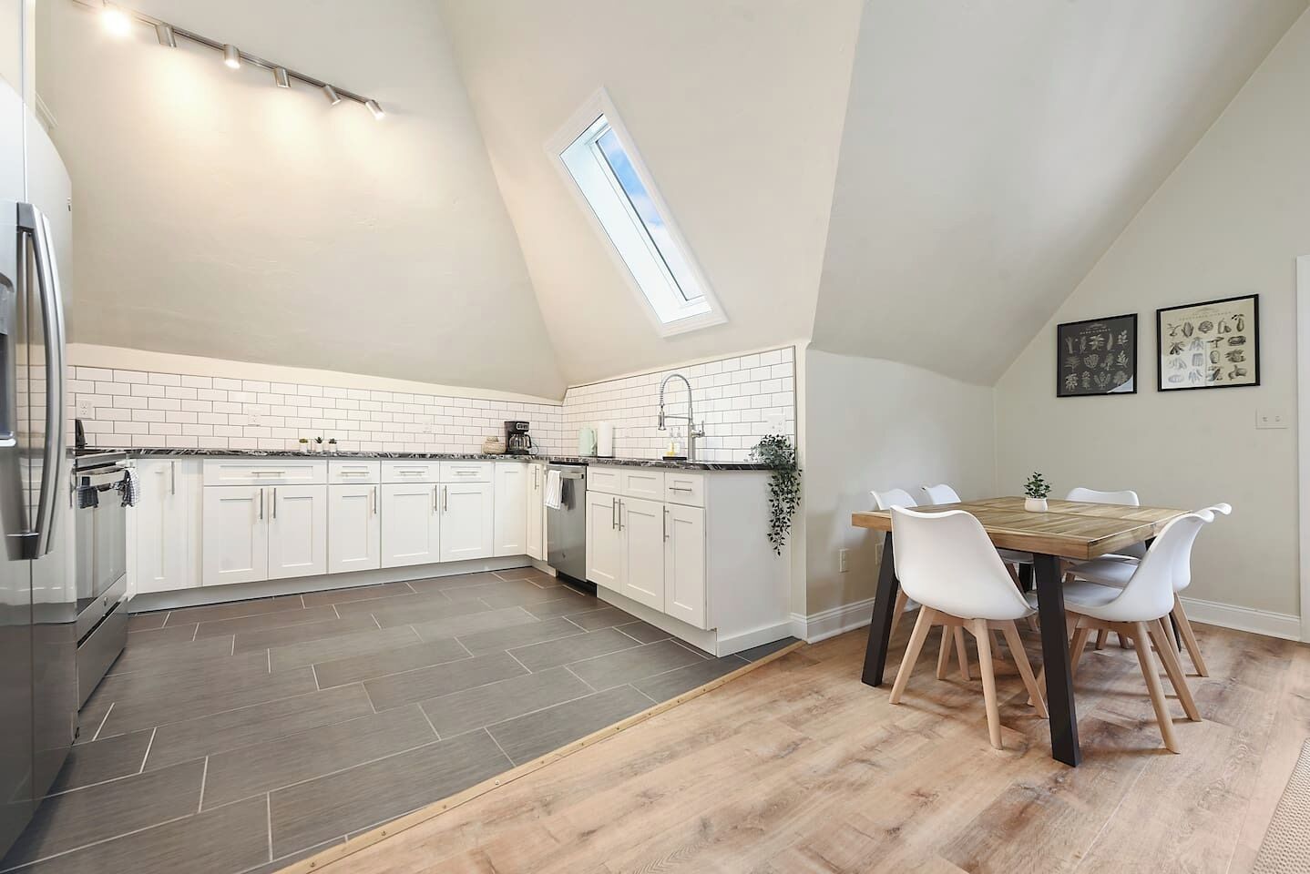 A modern kitchen with white cabinets, a black refrigerator, and a skylight.