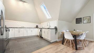 A modern kitchen with white cabinets, a black refrigerator, and a skylight.