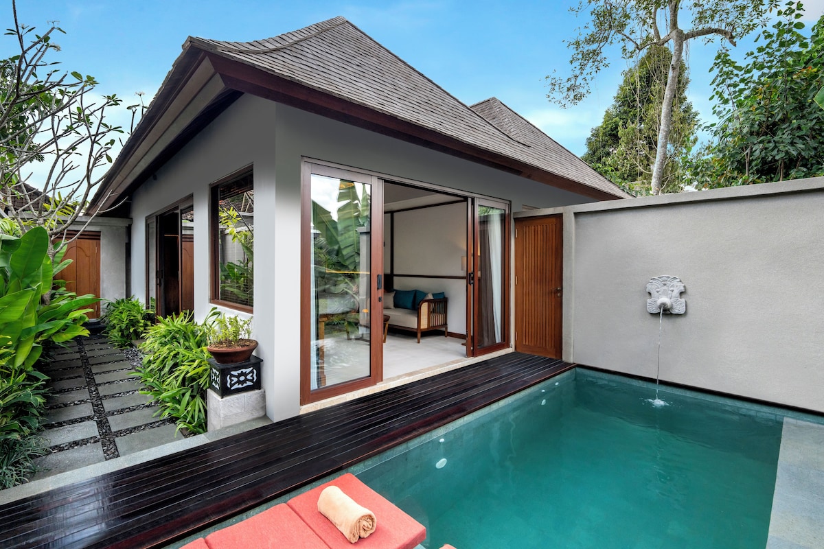 Una casa moderna con piscina, terraza de madera y puerta de vidrio que da a una sala de estar.
