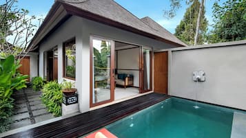 A modern house with a swimming pool, a wooden deck, and a glass door leading to a living area.