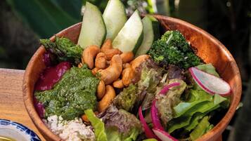 Uma tigela de madeira cheia de ingredientes para salada sobre uma mesa de madeira.