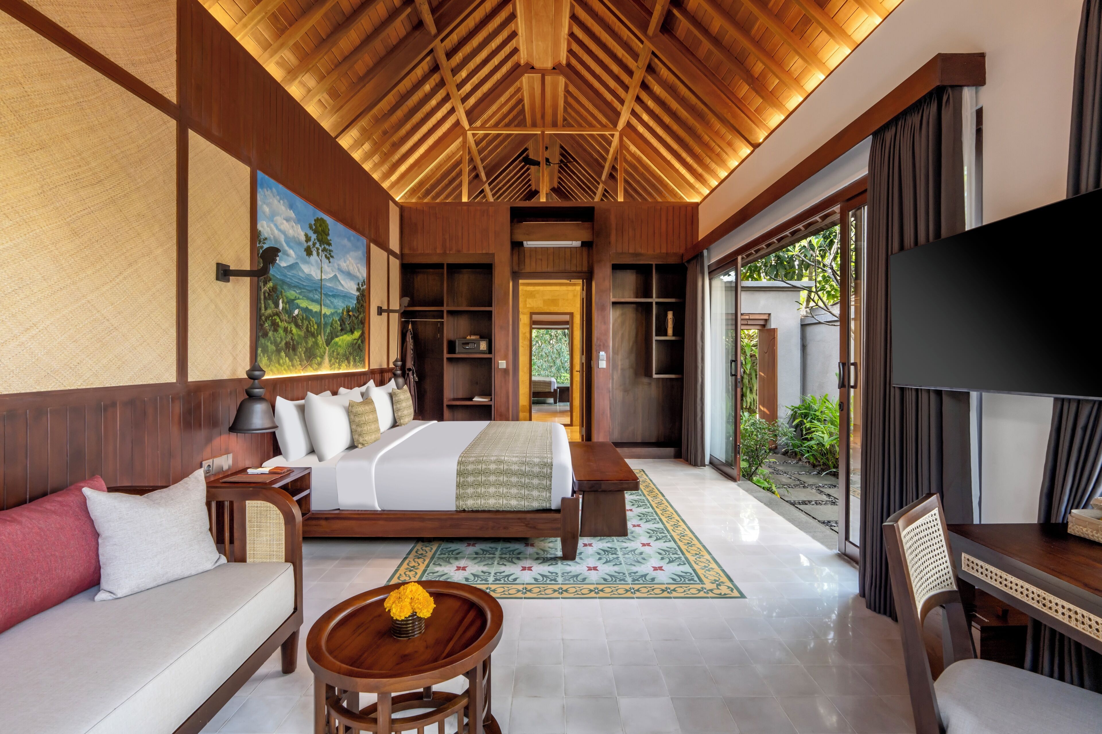 A hotel room with a bed, sofa, TV, and a view of the outdoors.