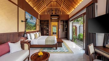 A hotel room with a bed, sofa, TV, and a view of the outdoors.