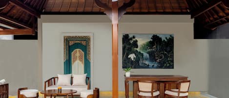 A room with a wooden ceiling, a sofa set, a dining table with chairs, a large painting, and a decorative pillar.