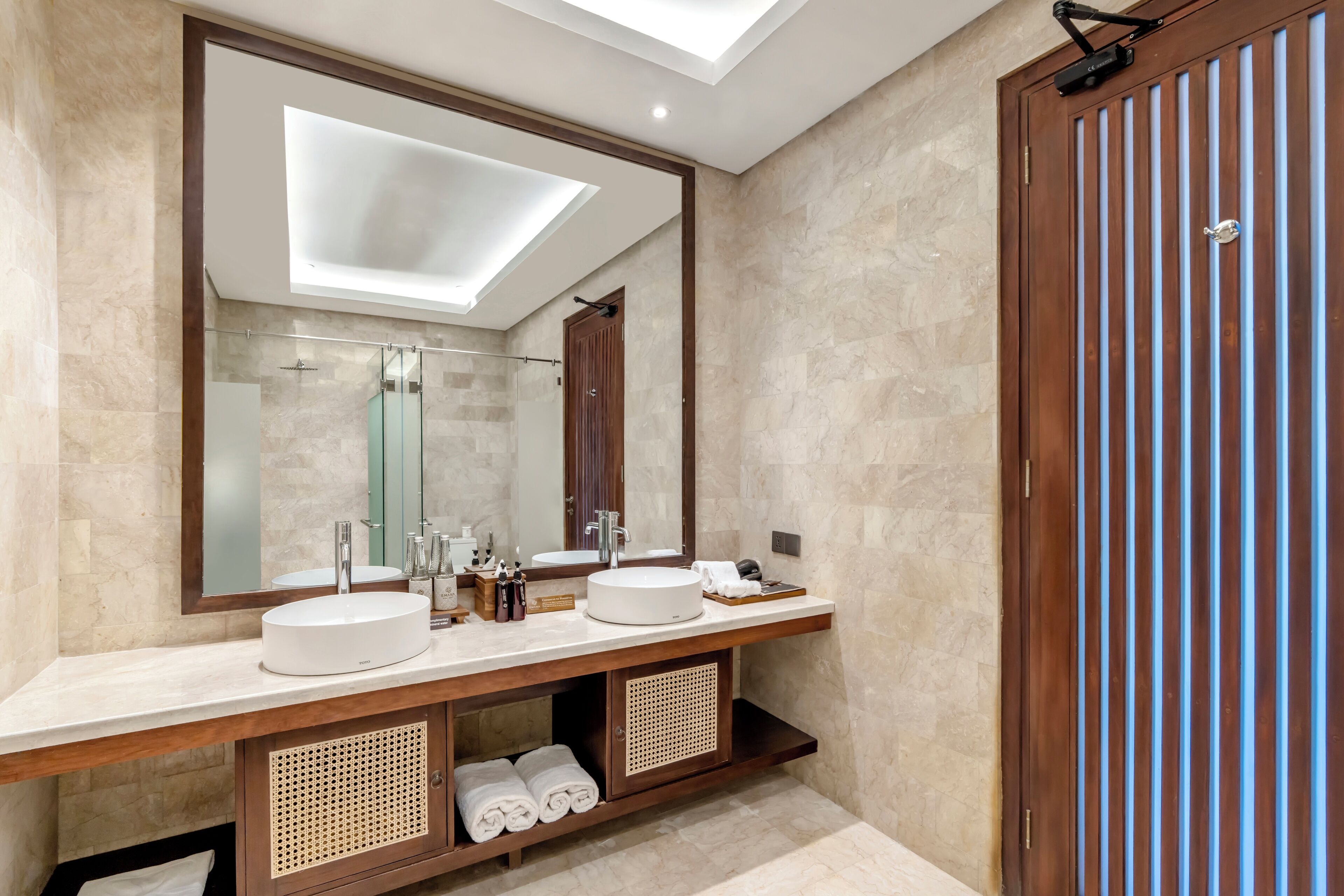 Un baño moderno con dos lavamanos, un espejo grande y una lámpara en el techo.