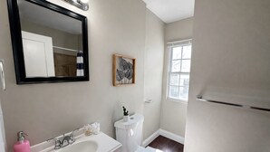Ein Badezimmer mit einem weißen Waschbecken, einer Toilette, einem Spiegel und einem Fenster.