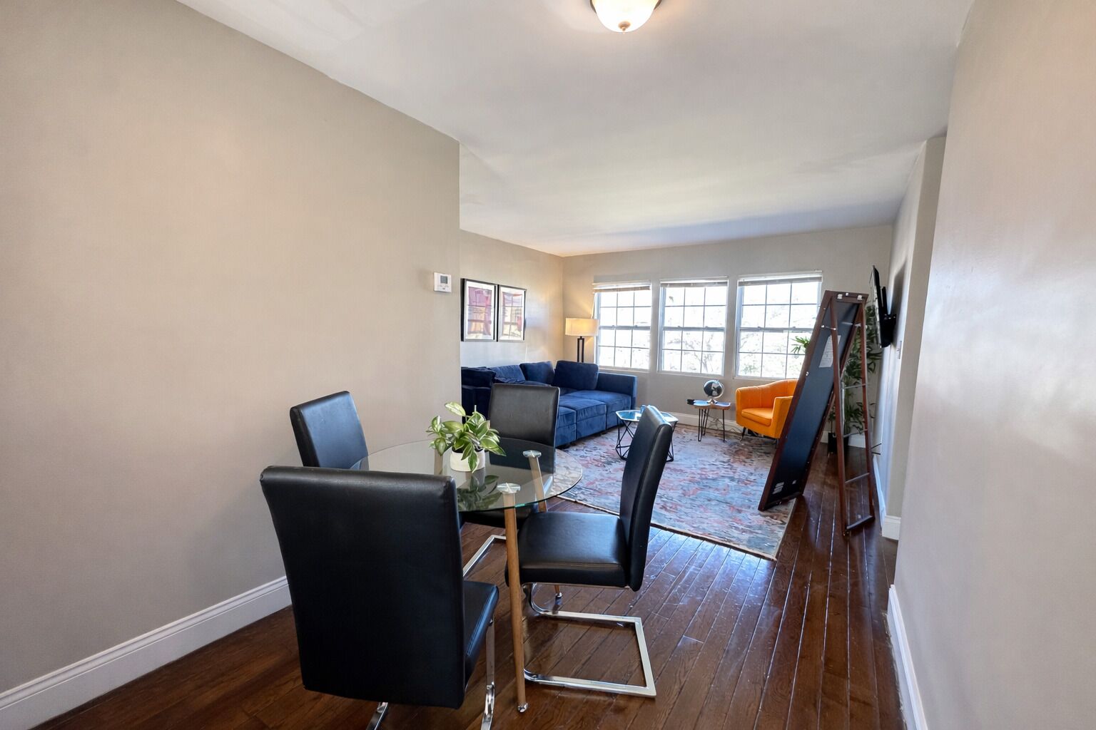 A dining area with a glass table and chairs, a sofa, and a ladder against the wall.