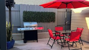 A patio with a grill, red chairs, and a table under a red umbrella. - Cozy Casita in the Valley (Lemon Grove)