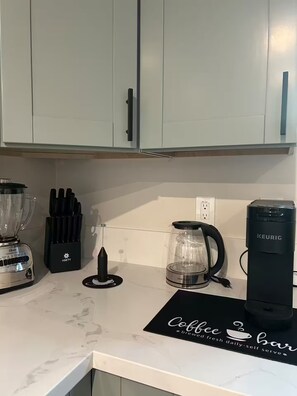 Et køkken med et skilt til kaffebar, en blender, kaffemaskine og elkedel.