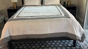 A bed with a headboard, two bedside tables with lamps, a patterned rug, and two wall-mounted paintings. - Cozy Casita in the Valley (Lemon Grove)