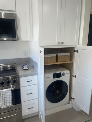 A compact kitchen with a stainless steel range, a microwave, and a built-in washing machine. - Lovely 1-bedroom ADU with AC-mini Split in vibrant Anaheim (Anaheim)