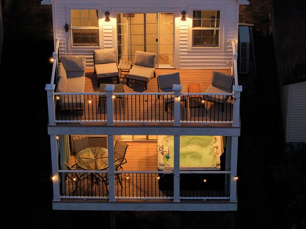 A two-story house with a balcony, outdoor seating, and a hot tub.