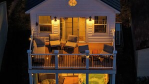 A two-story house with a balcony, a hot tub, and a patio area with furniture.